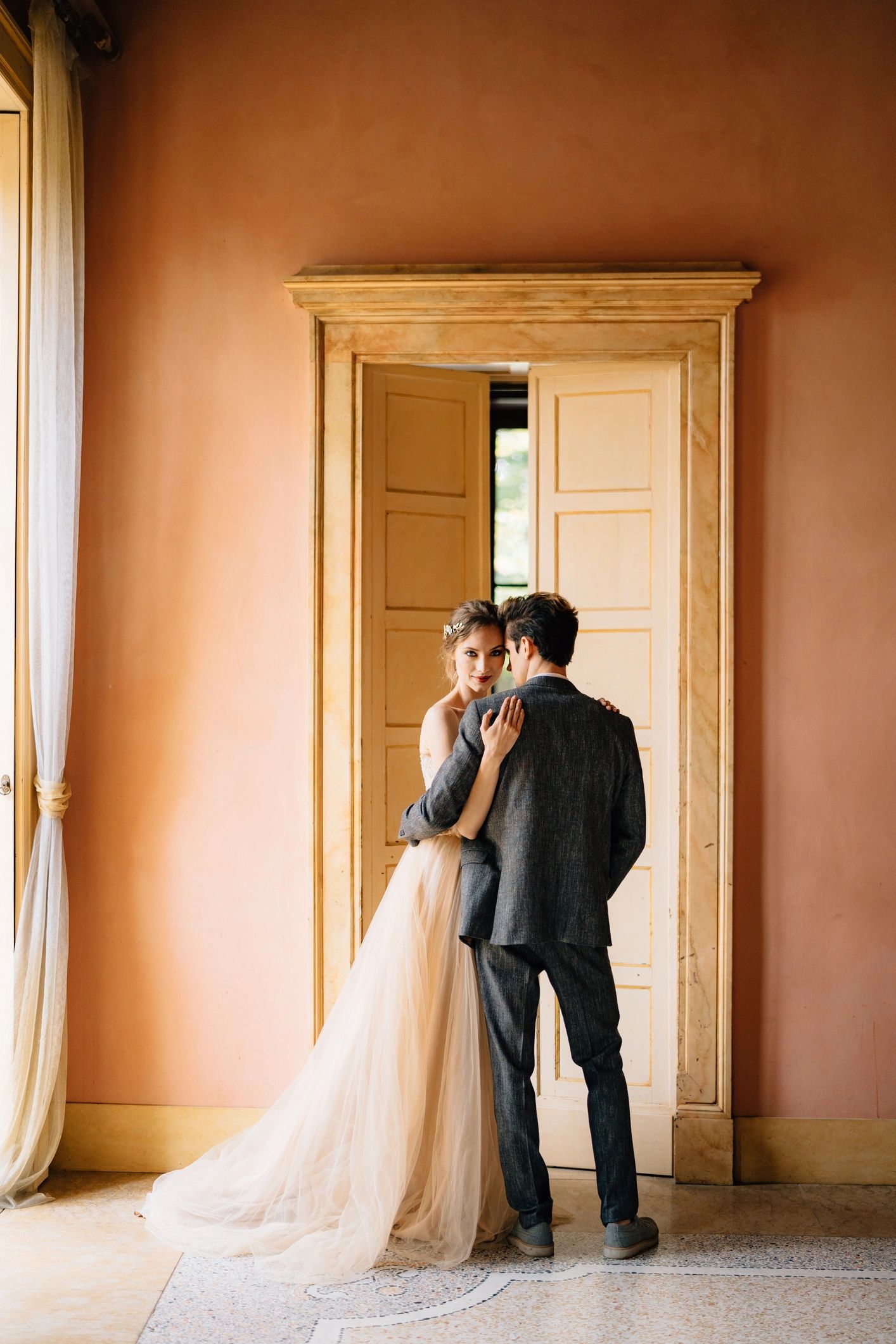 Bride and groom standing near a doorway in soft light