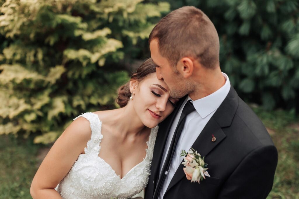 A bride and groom are hugging each other in a garden