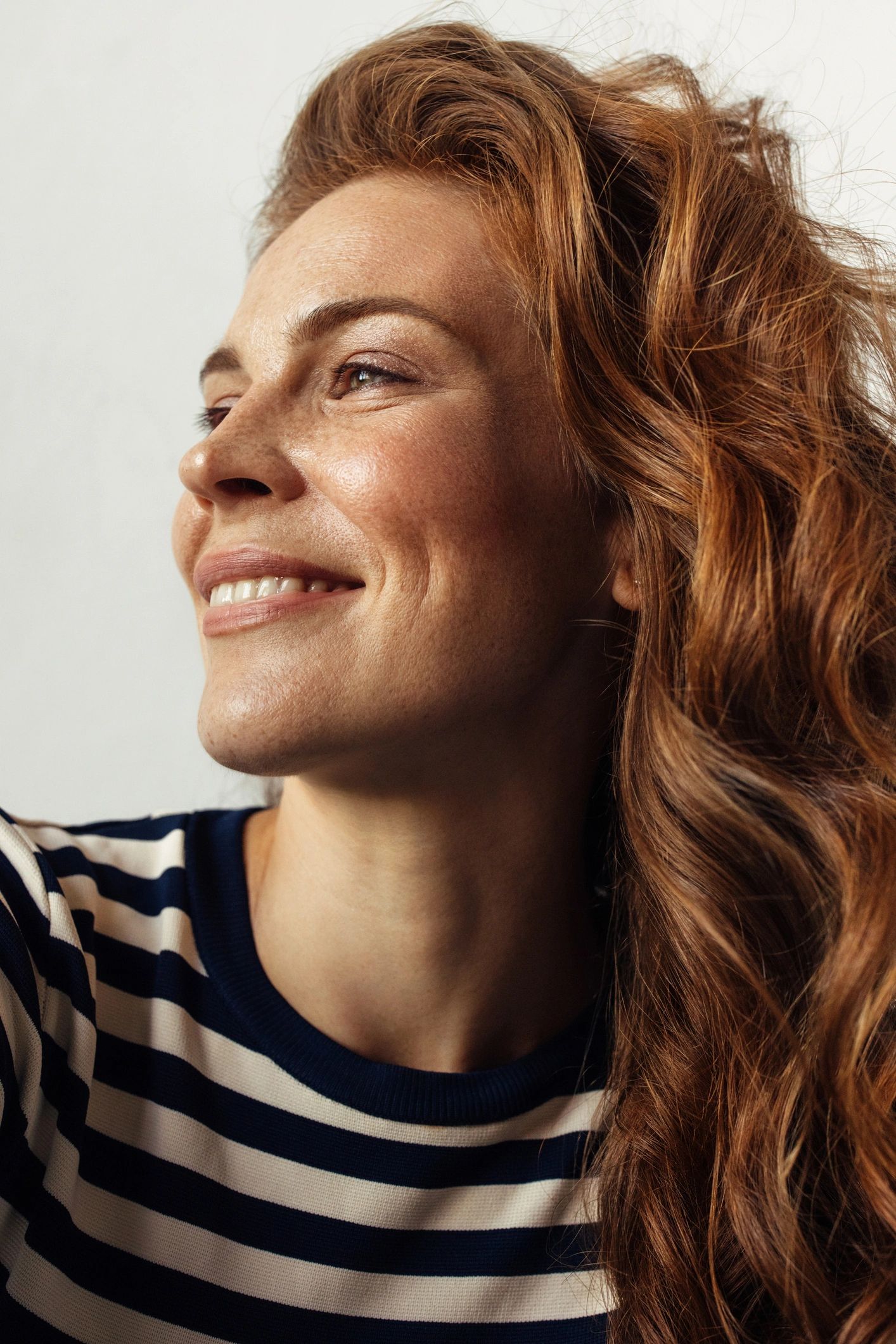Smiling woman with flowing red hair in striped shirt